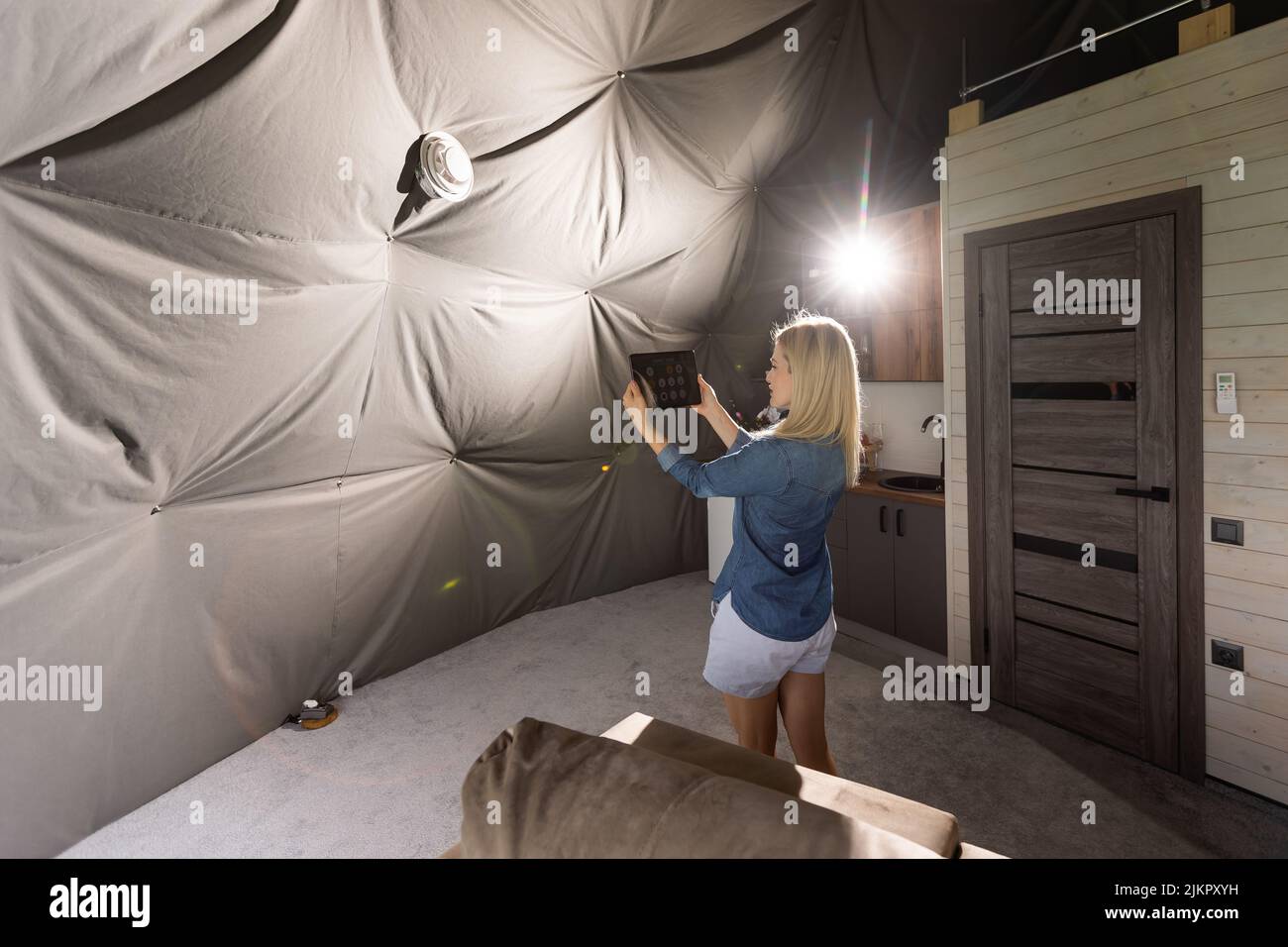 femme avec une tablette qui active le système de ventilation comme récupérateur pour la qualité de l'air frais à l'intérieur, maison intelligente Banque D'Images