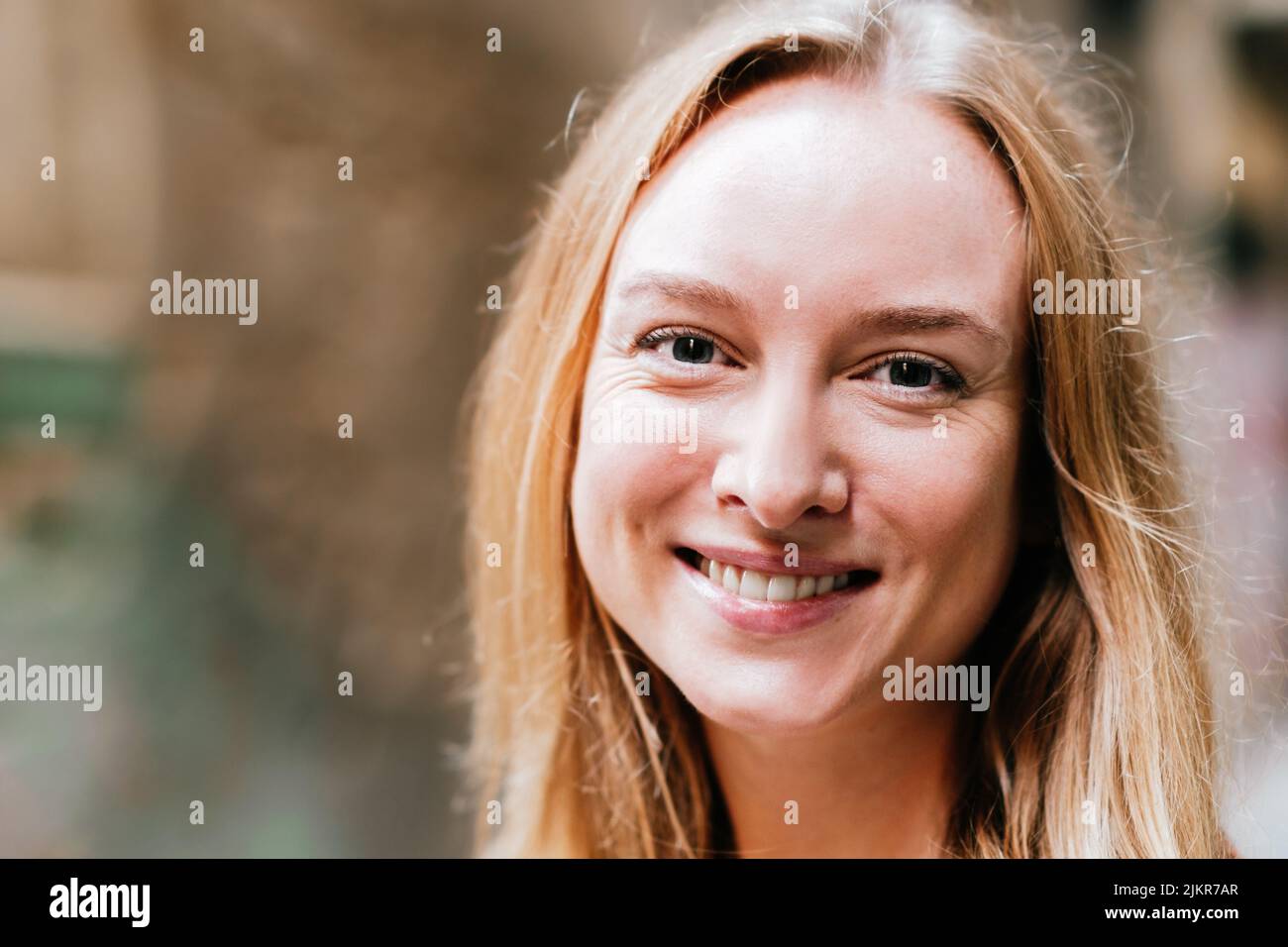portrait horizontal rapproché d'une jeune femme blonde sereine et attrayante. Elle regarde la caméra avec un sourire agréable Banque D'Images