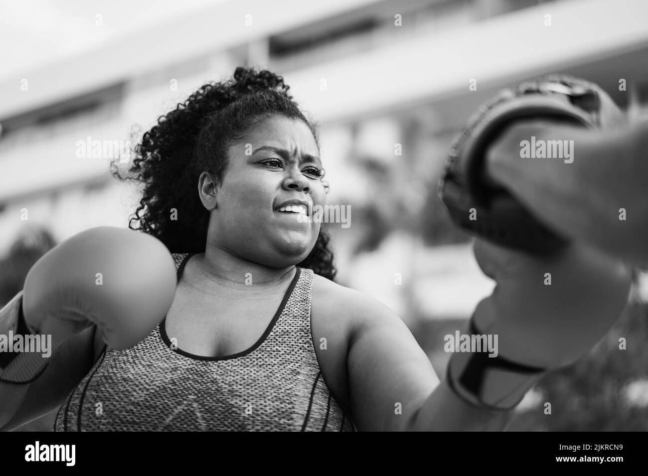 Femme africaine curvy et entraîneur personnel faisant la séance d'entraînement de boxe en extérieur - Focus sur le visage - montage noir et blanc Banque D'Images