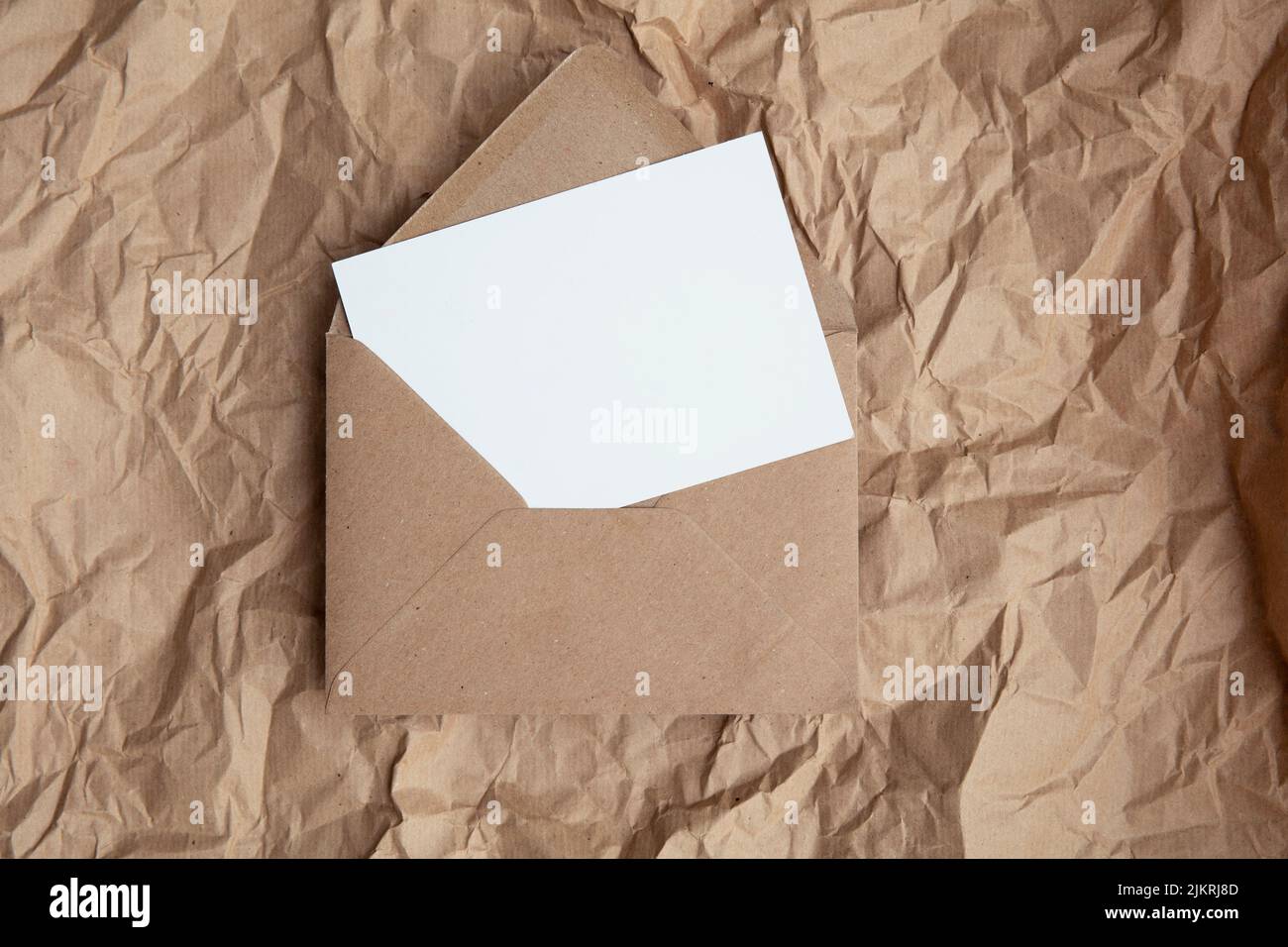 Maquette de carte vierge avec modèle d'enveloppe en papier kraft brun sur papier brun froissé Banque D'Images