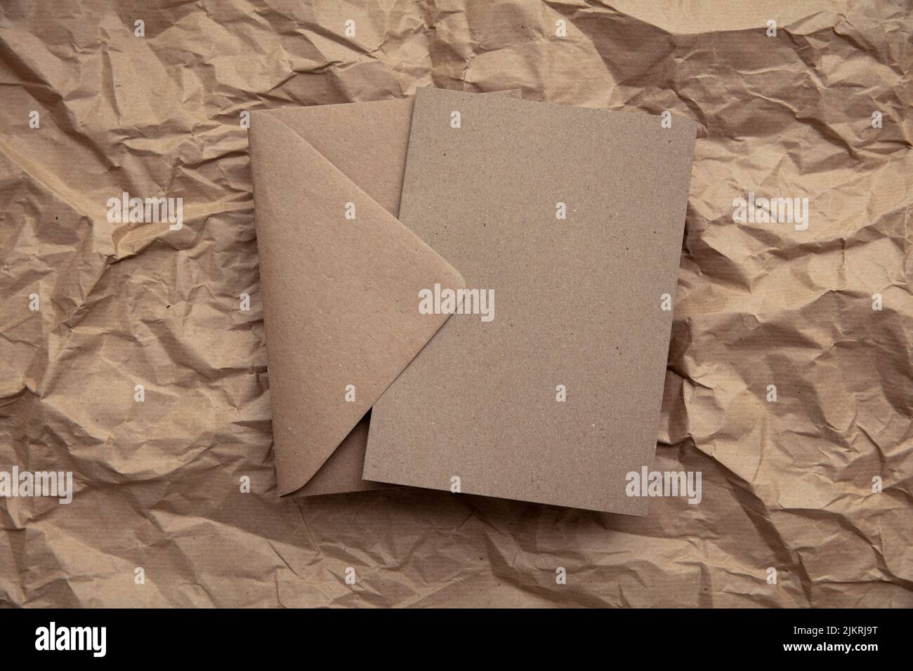Maquette de carte vierge avec modèle d'enveloppe en papier kraft brun sur papier brun froissé Banque D'Images