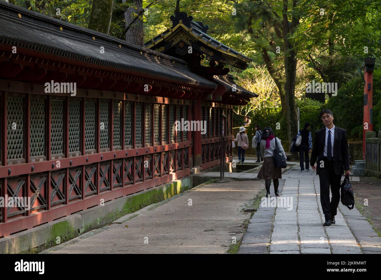 Un salaryman et des touristes marchent dans le domaine du sanctuaire de Nezu à Bunkyo Ward, Tokyo, Japon. Banque D'Images
