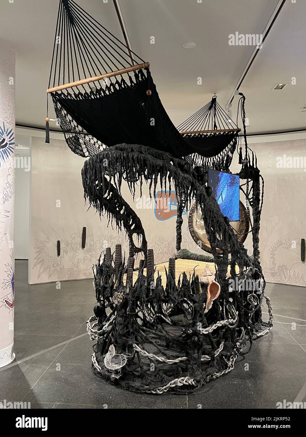 Guadalupe Maravilla (née El Salvador, 1976). Lanceur de maladies n° 0, 2022. Gong, hamac, TV LCD, cendres cérémonielles, cristaux de pyrite, roche volcanique, acier, bois, coton, mélange de colle, plastique, loofah, objets recueillis d'un rituel de retracing de la route de migration originale de l'artiste, 118 × 123 × 64 po. (299,7 × 312,4 × 162,6 cm). Avec l'aimable autorisation de l'artiste et de P·P·O·W, New York. © Guadalupe Maravilla.cet art est profondément influencé par son enfance en El Salvador tout au long des années '70s et '80s, quand le pays a été consommé par une guerre civile sanglante. Banque D'Images