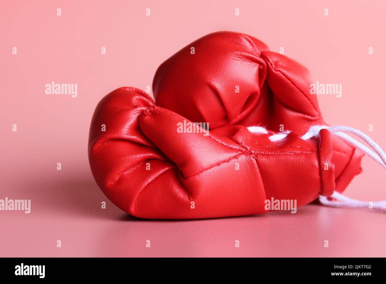 Gros plan sur des gants de boxe rouges sur fond rose. Concept sportif Banque D'Images