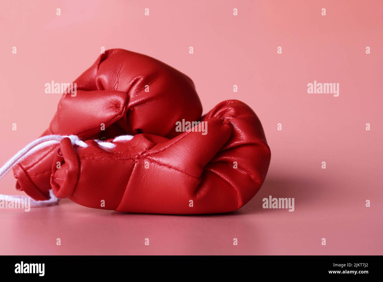 Gros plan sur des gants de boxe rouges sur fond rose. Concept sportif Banque D'Images