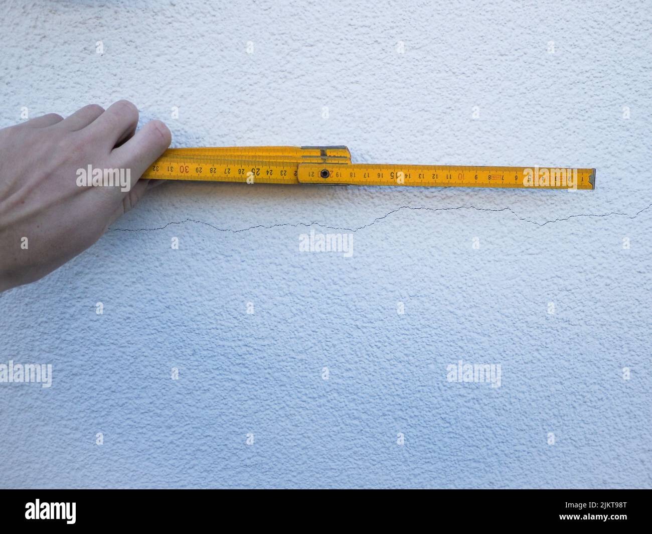 Main tenant une règle pliante au mur. Banque D'Images