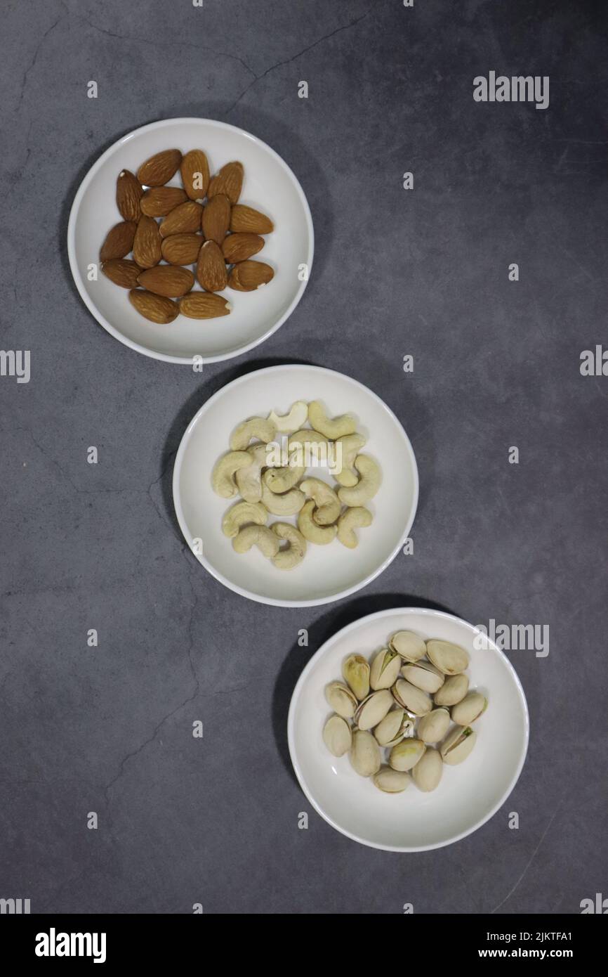 Une vue de dessus de pistaches avec des amandes et des noix de cajou dans de petits bols blancs Banque D'Images