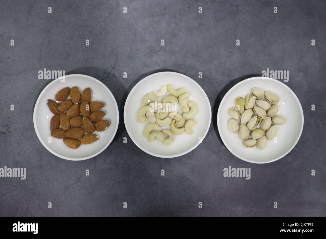 Une vue de dessus de pistaches avec des amandes et des noix de cajou dans de petits bols blancs Banque D'Images