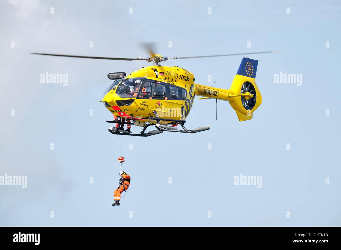 Une personne descend d'un hélicoptère de sauvetage ADAC stationnaire, en vol. Ambulance aérienne allemande, infrastructure de recherche et de sauvetage. Banque D'Images