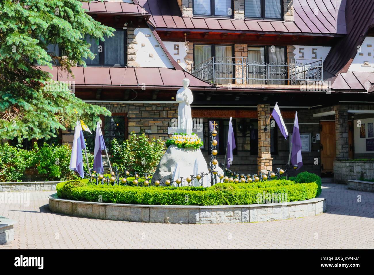 La statue blanche est entourée d'une haie verte et d'une clôture en pierre. Varsovie, Pologne. Banque D'Images