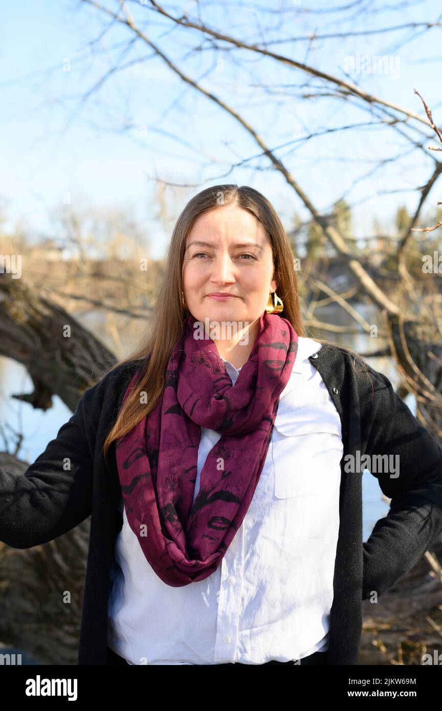 Une femme confiante à l'extérieur devant une rivière se tient devant un arbre Banque D'Images