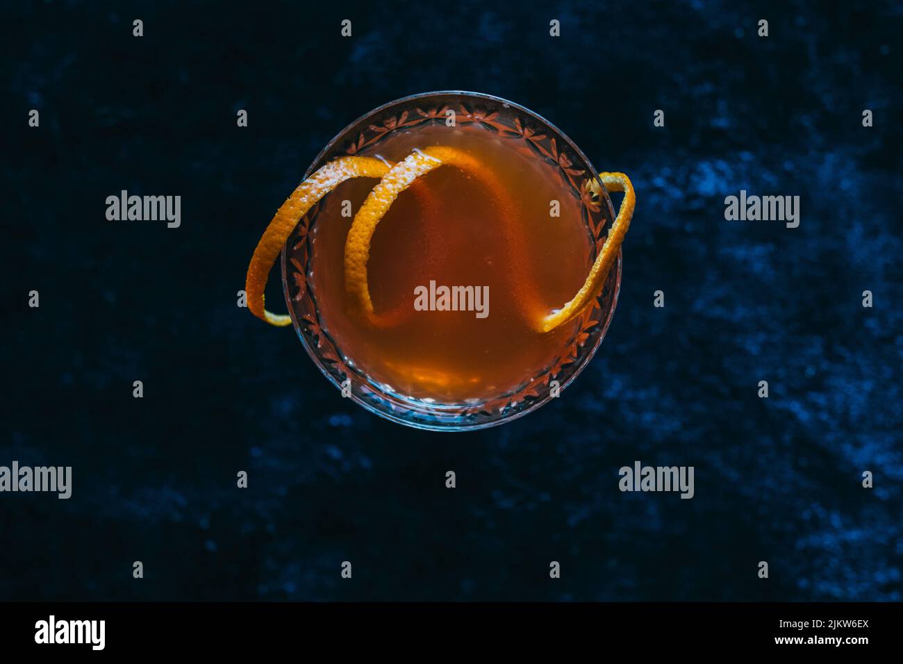 cocktail d'orange pétillant en verre coupé cristal sur tapis de velours bleu foncé, directement au-dessus Banque D'Images