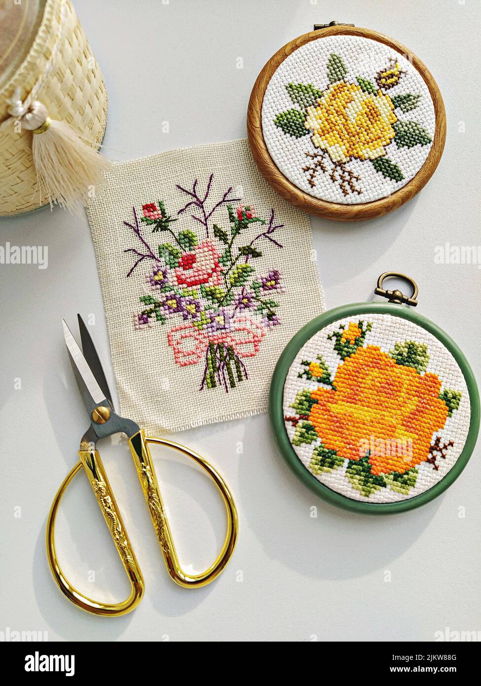 Cerceaux, ciseaux, aiguilles, fil et tissu en bois vintage brodés avec broderie fleurie sur blanc, plat Banque D'Images