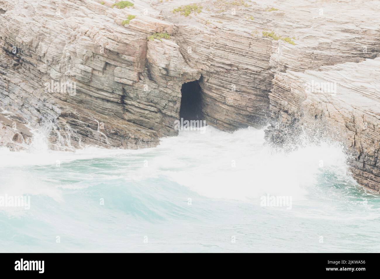 Belle grotte située dans les falaises de punta corveira, frappée par les vagues pendant un jour pluvieux, située à Lugo, Espagne. Banque D'Images