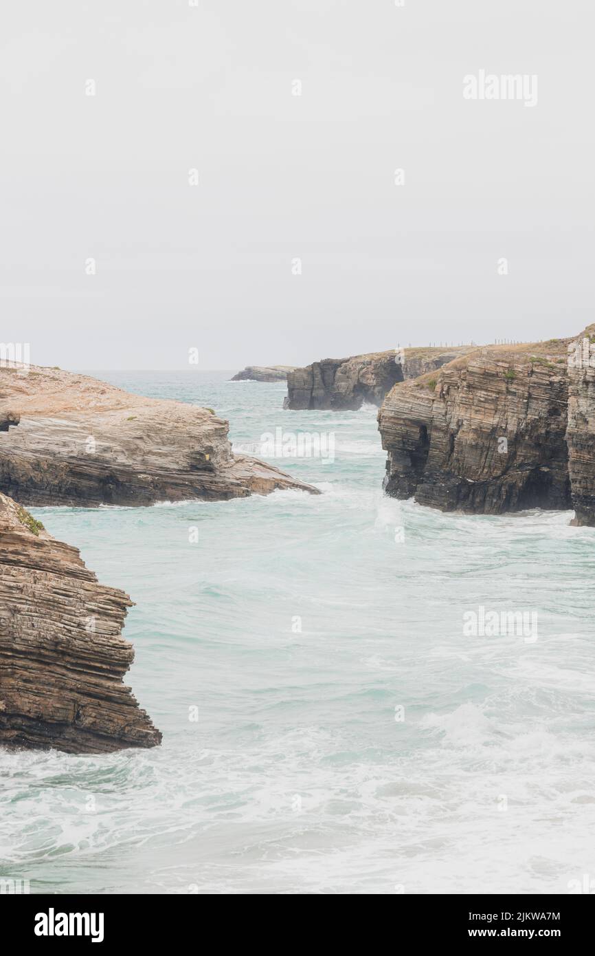 Falaises situées dans la plage touristique des cathédrales à Lugo, Espagne, pendant un jour pluvieux, avec vagues et marée haute, tir vertical. Banque D'Images