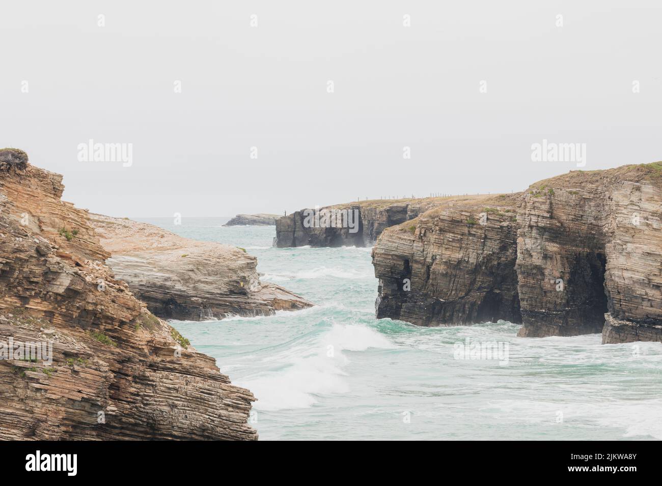 Falaises situées dans la plage touristique des cathédrales à Lugo, en Espagne, pendant une journée de pluie, avec des vagues et une marée haute. Banque D'Images