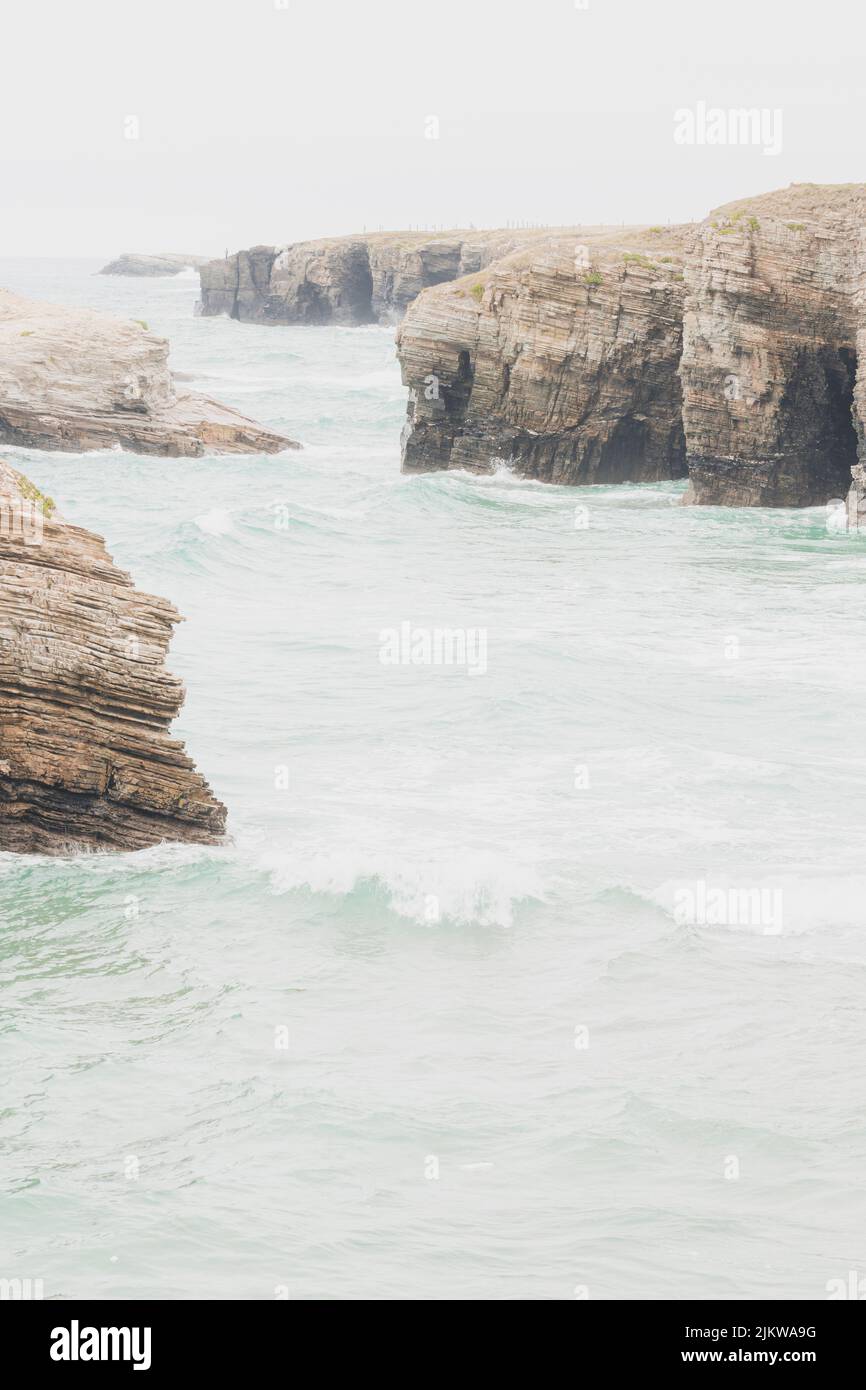 Falaises situées dans la plage touristique des cathédrales à Lugo, en Espagne, pendant une journée de pluie, avec des vagues et une marée haute. Banque D'Images