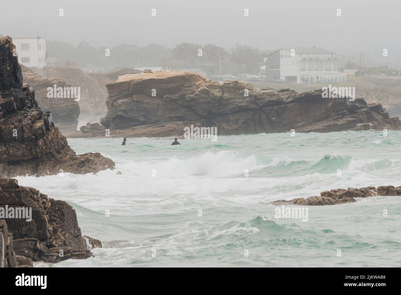 Surfeurs à Punta Corveira, Lugo, Espagne, pendant une journée de forte houle et de pluie. Banque D'Images