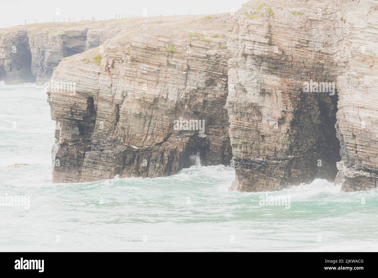 Falaises situées dans la plage touristique des cathédrales à Lugo, en Espagne, pendant une journée de pluie, avec des vagues et une marée haute. Banque D'Images