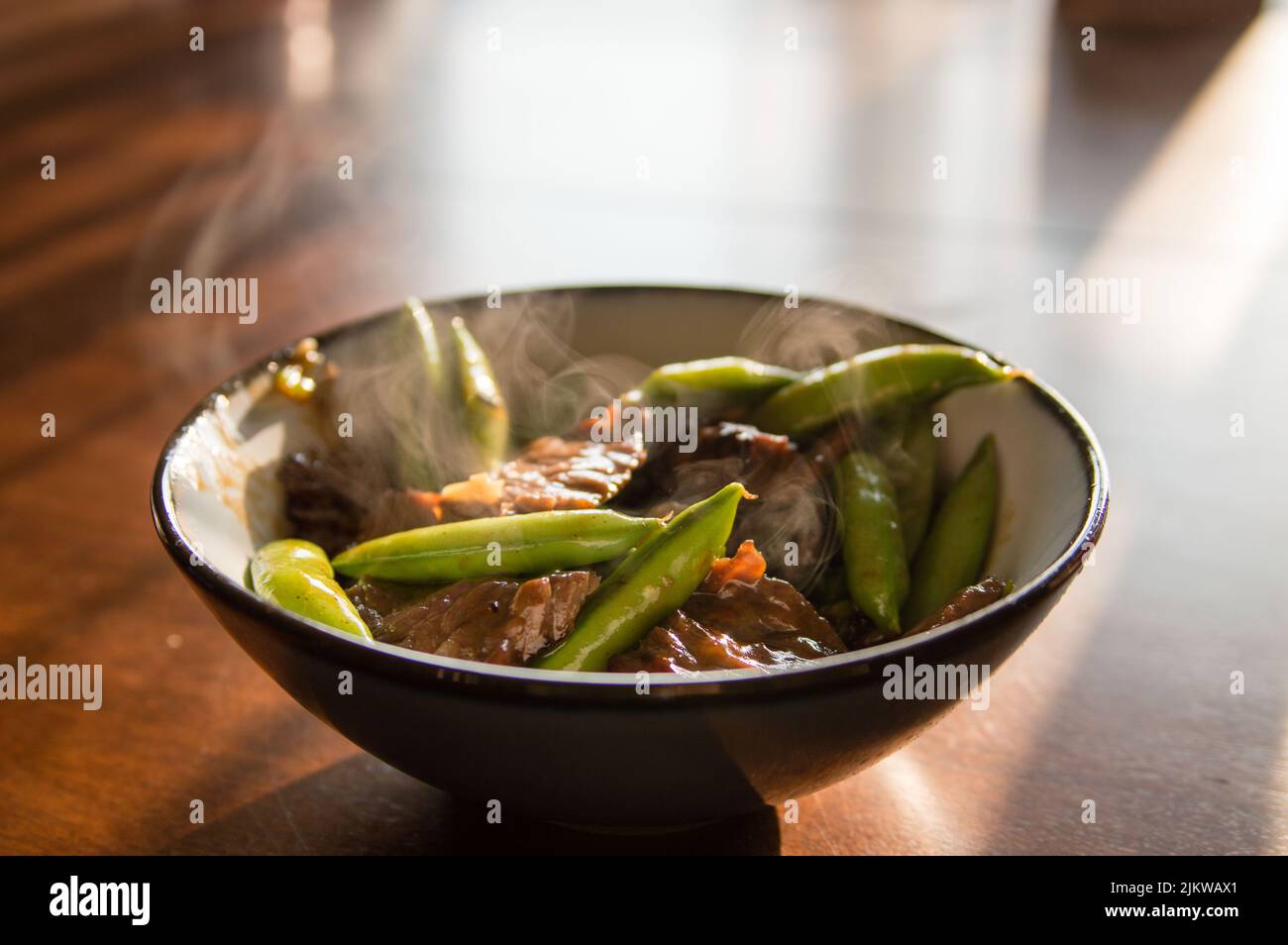 A hot dish of the stir fry beef with peas in a bowl on the wooden table Banque D'Images