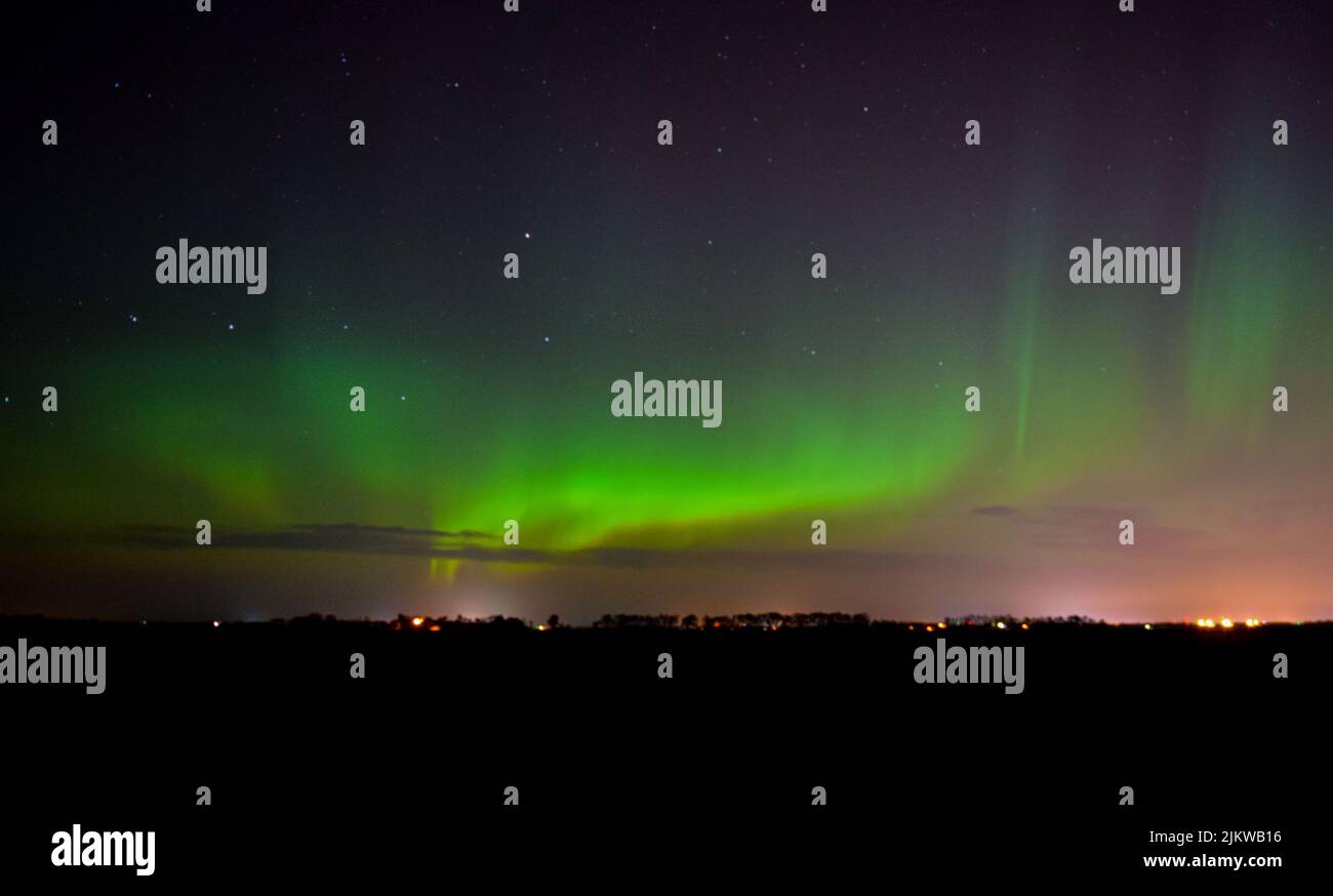 An aerial view of a cityscape at night with the northern lights in the sky Banque D'Images