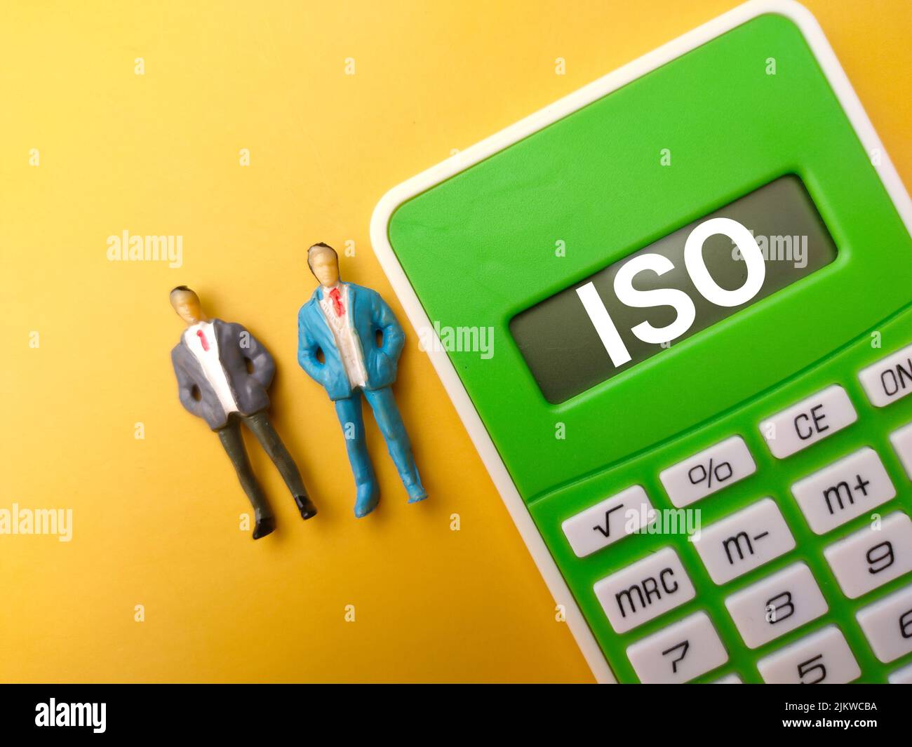 Vue de dessus miniature personnes et calculatrice avec texte ISO sur fond jaune. Banque D'Images