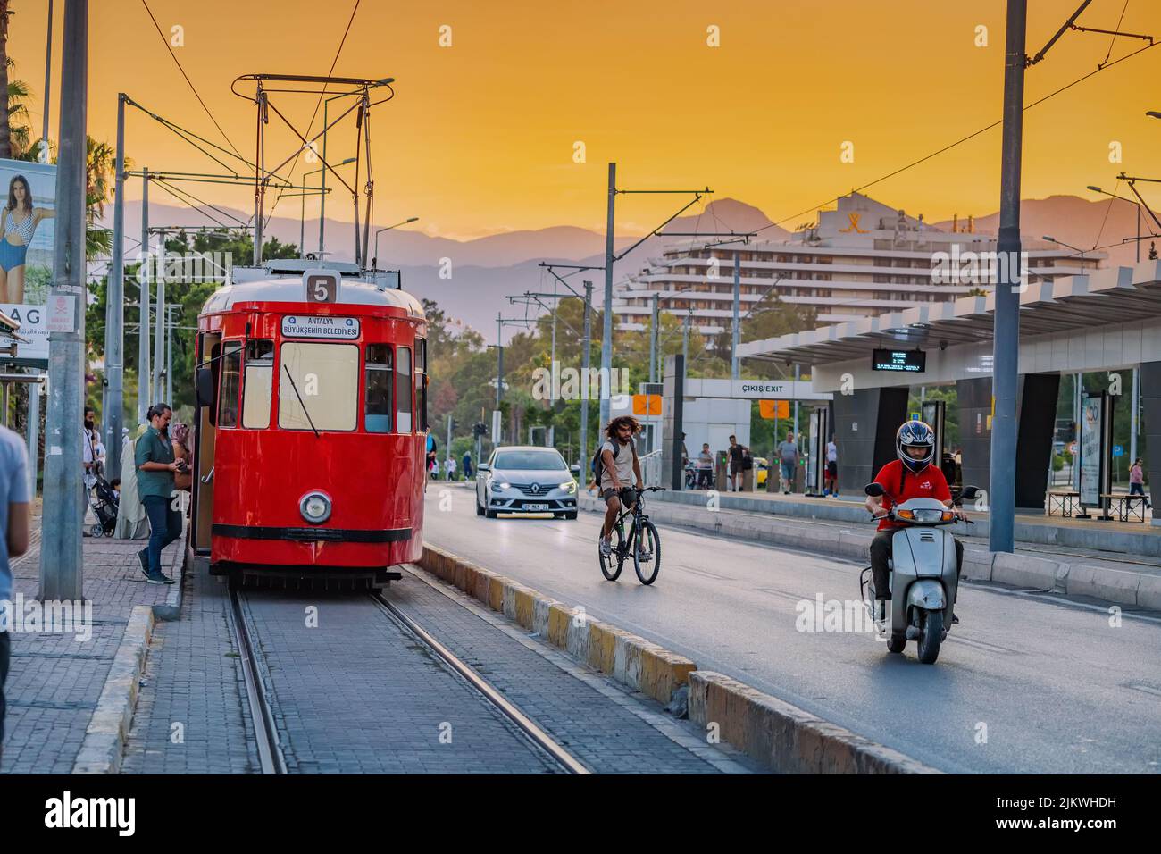 17 juin 2022, Antalya, Turquie : tramway rétro rouge avec passagers, voitures et motards dans la rue de la ville à l'heure de pointe. Concept de transport public Banque D'Images