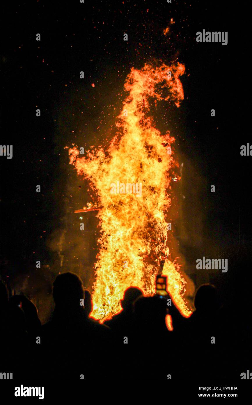 Une photo verticale d'un énorme feu avec des personnes qui l'entourent Banque D'Images