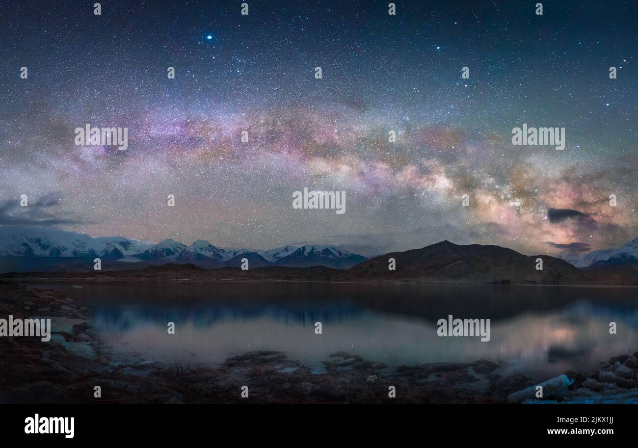 Une belle vue sur un lac entouré de collines sous le ciel nocturne avec la galaxie de la voie lactée Banque D'Images