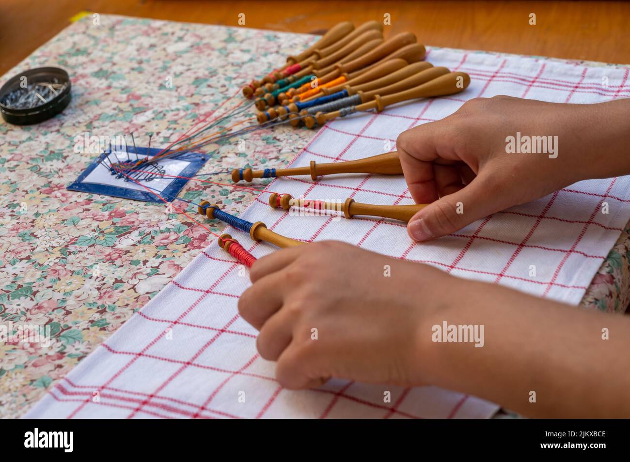 Mains de l'enfant faisant la dentelle de bobbin. Fils de dentelle colorés. Compétence et créativité. Banque D'Images