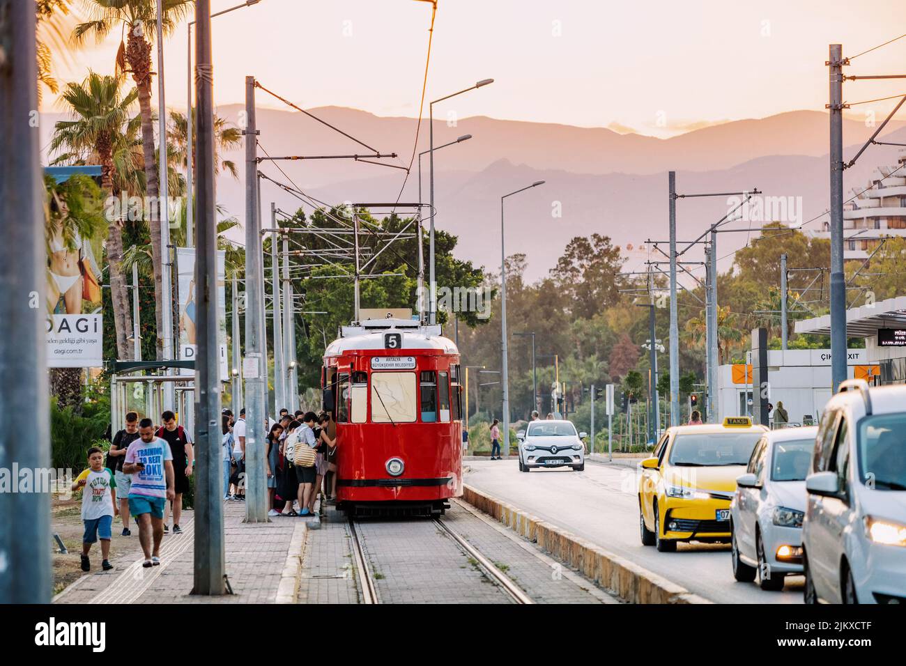 17 juin 2022, Antalya, Turquie : tramway rétro rouge avec passagers, voitures et motards dans la rue de la ville à l'heure de pointe. Concept de transport public Banque D'Images