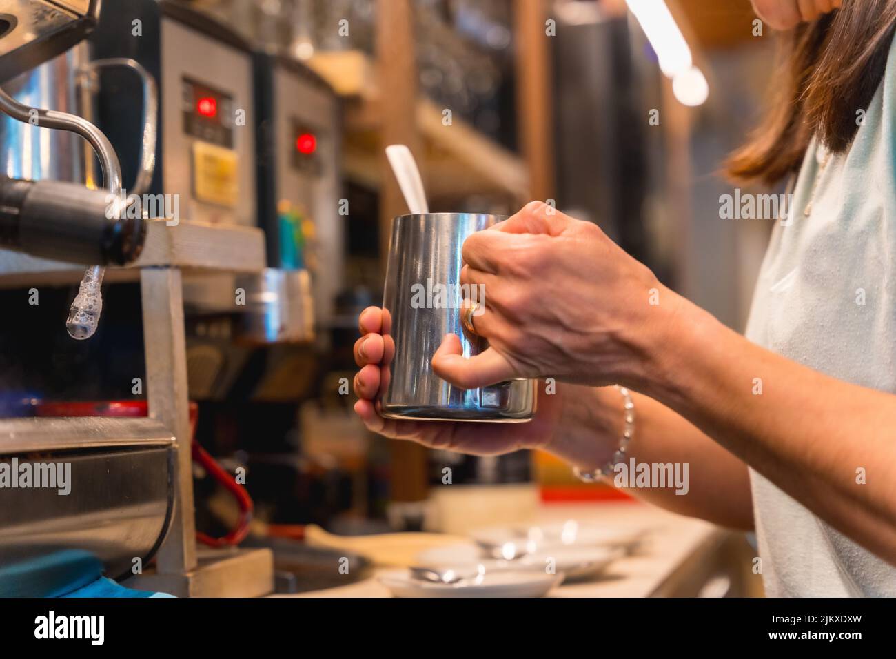 Une serveuse méconnaissable à la cafétéria femme prépare du café dans une machine à café, les restrictions dues au covid sont levées et l'utilisation obligatoire o Banque D'Images