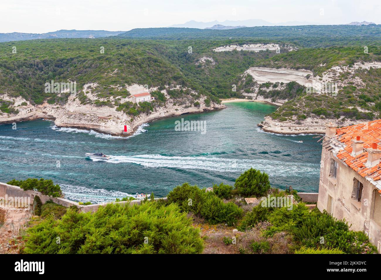 Bonifacio, Corse. Vue sur la côte avec des bateaux à moteur naviguant dans le port intérieur par une journée d'été Banque D'Images