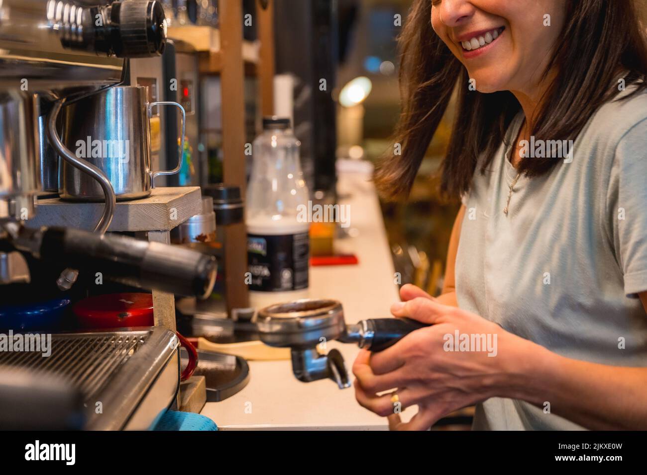Une serveuse de cafétéria souriante et méconnaissable prépare du café dans une machine à café, les restrictions de covid sont levées et l'utilisation obligatoire du Mas facial Banque D'Images