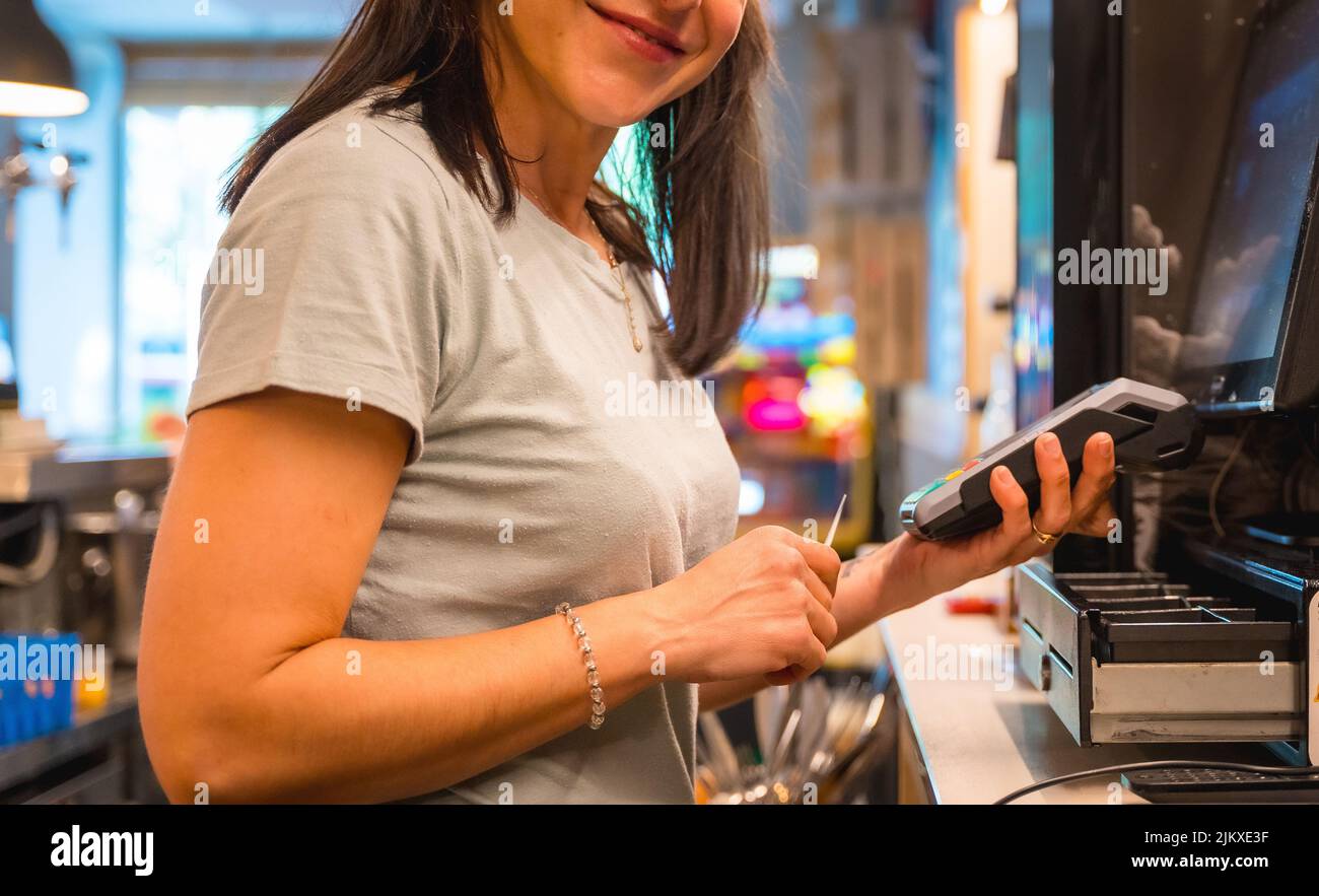 Une serveuse méconnaissable se chargeant par carte au café-restaurant Banque D'Images