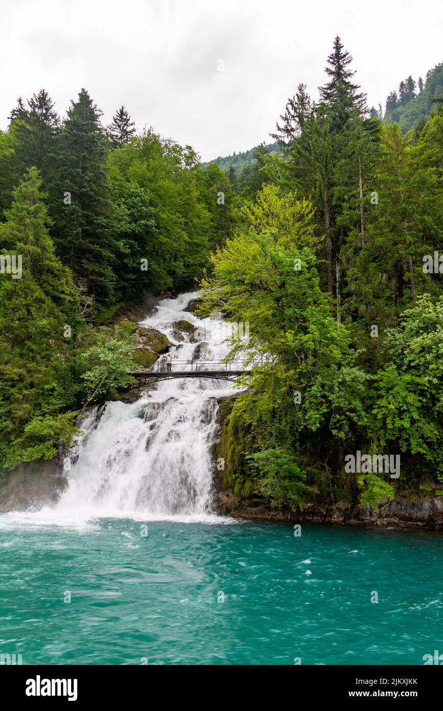 Une photo verticale d'une personne sur un pont au-dessus de cascades avec le lac de Brienzersee à Interlaken, Suisse, Europe Banque D'Images