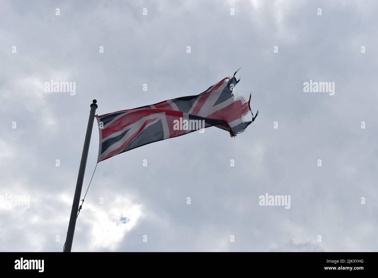 Un drapeau Union Jack en lambeaux contre un ciel nuageux. Banque D'Images