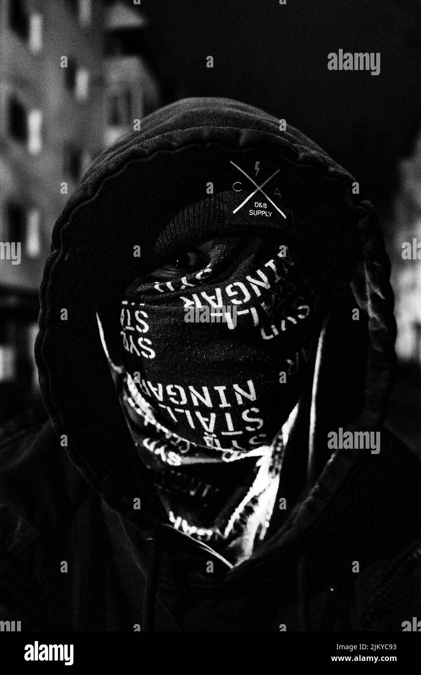 Une photo en niveaux de gris d'un homme avec un masque à capuchon et plein visage couvert avec un œil apparaît dans la rue Banque D'Images