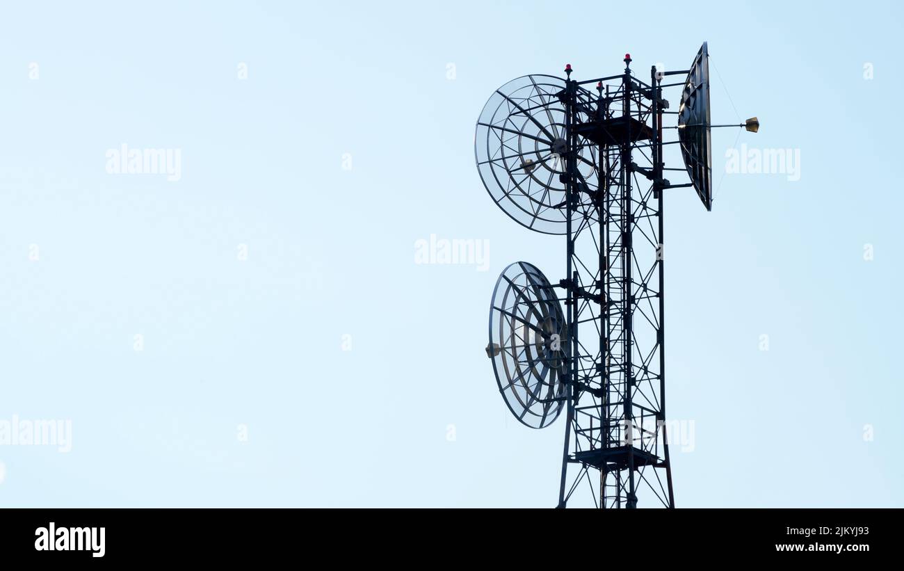 Pylône avec antennes paraboliques rondes pour la transmission et la répétition de signaux TV isolés sur fond de ciel homogène avec espace de copie Banque D'Images