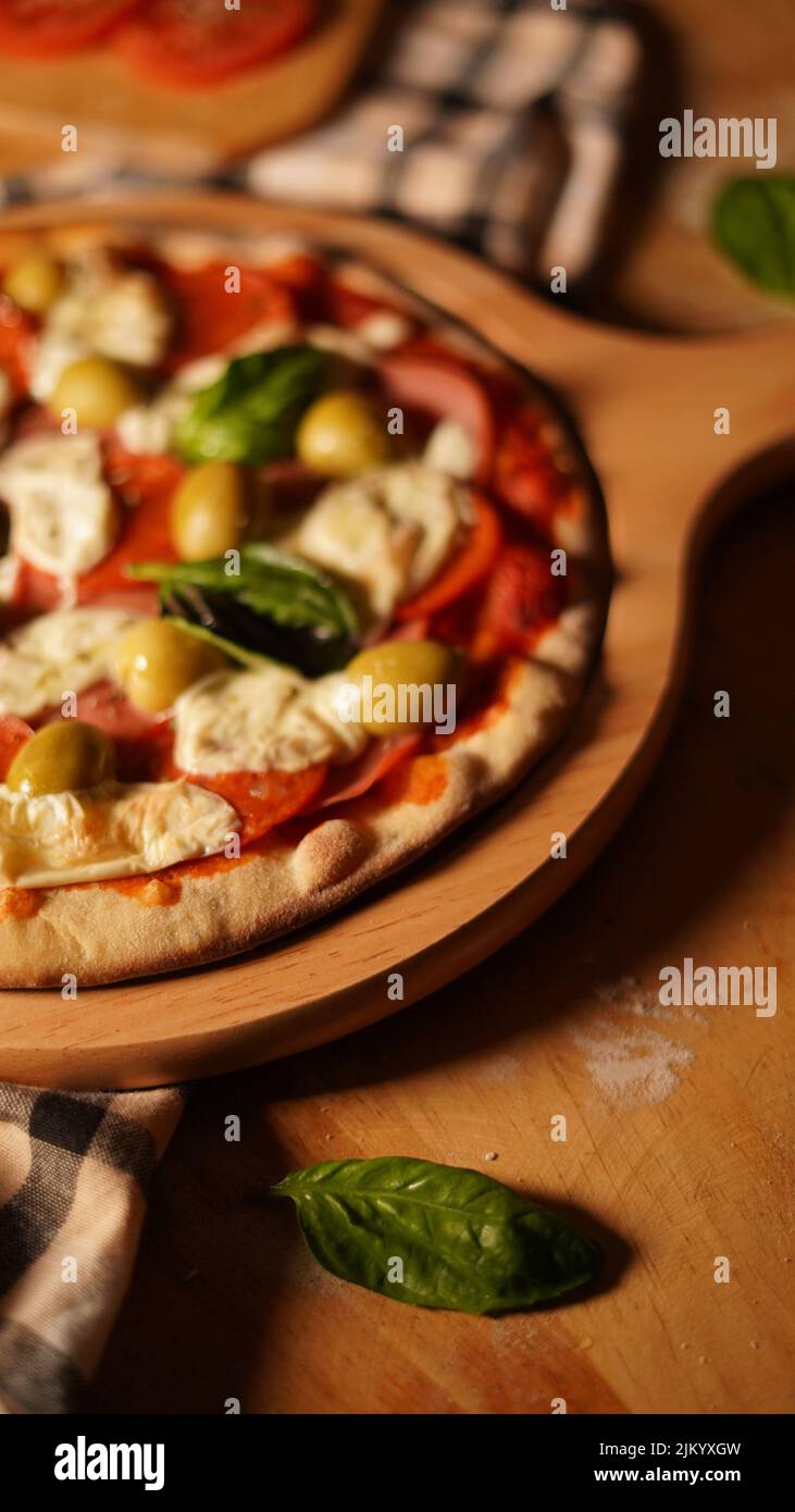 A vertical shot of a freshly made pizza margarita on a wooden board Banque D'Images