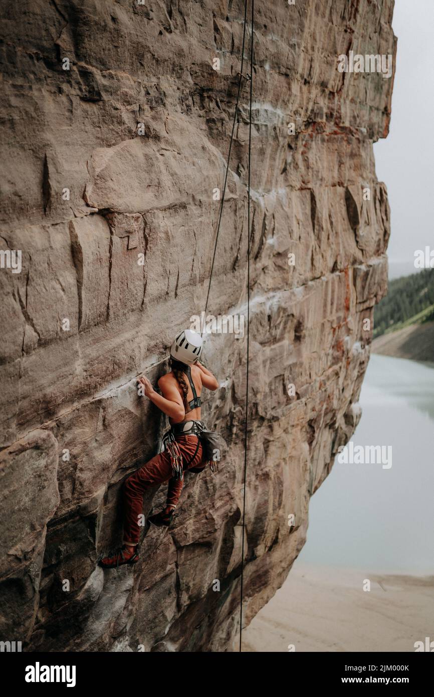 Gros plan d'un grimpeur adulte femelle sur une falaise près d'un lac Banque D'Images