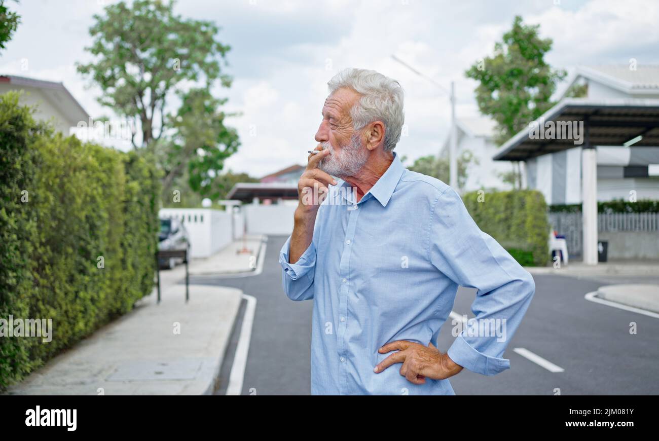 Un vieil homme âgé qui fume de la cigarette à l'extérieur, la dépendance à la fumée, le mauvais habbit. Banque D'Images