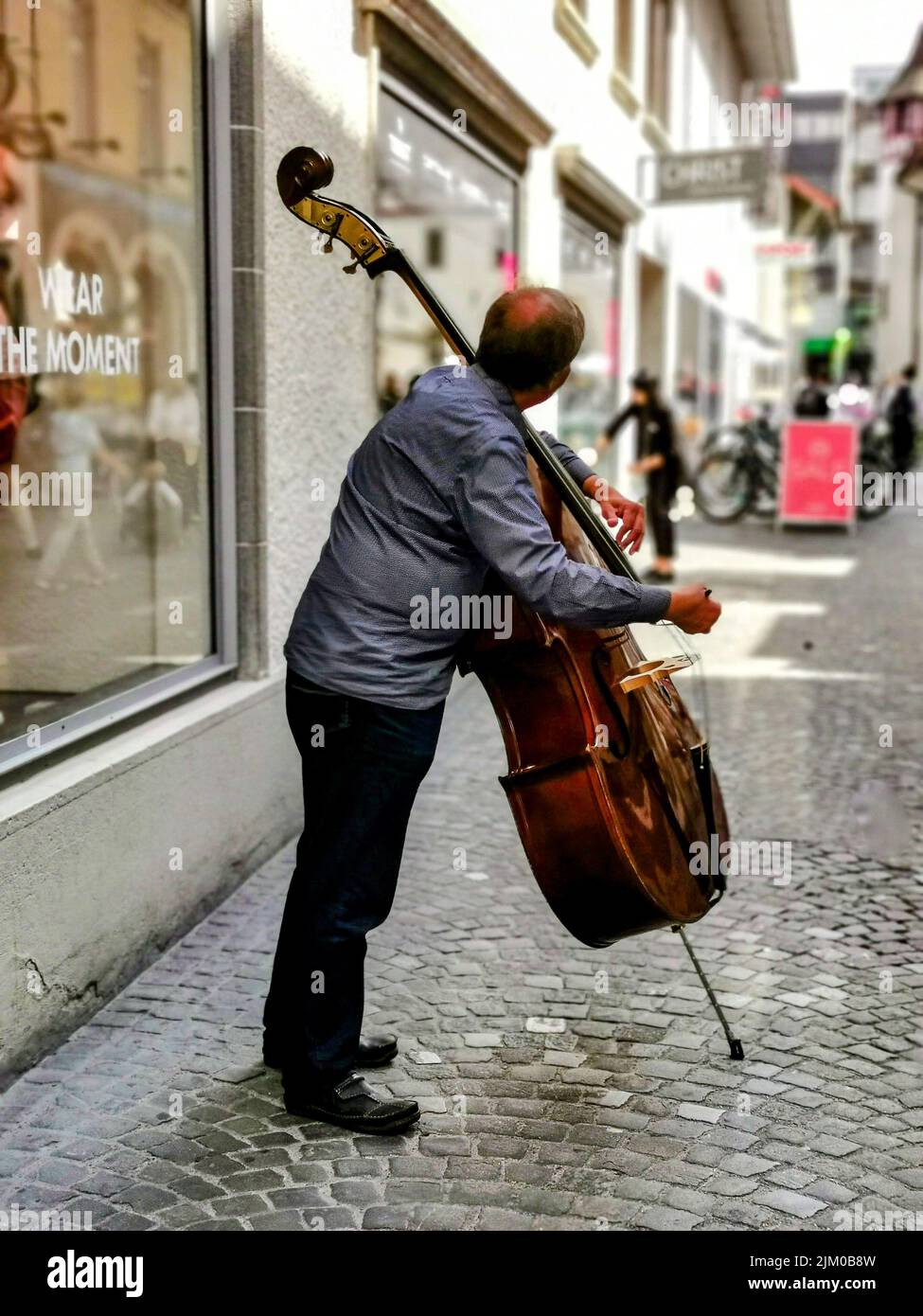 Photo verticale d'un homme adulte jouant sur une double basse dans la rue Banque D'Images