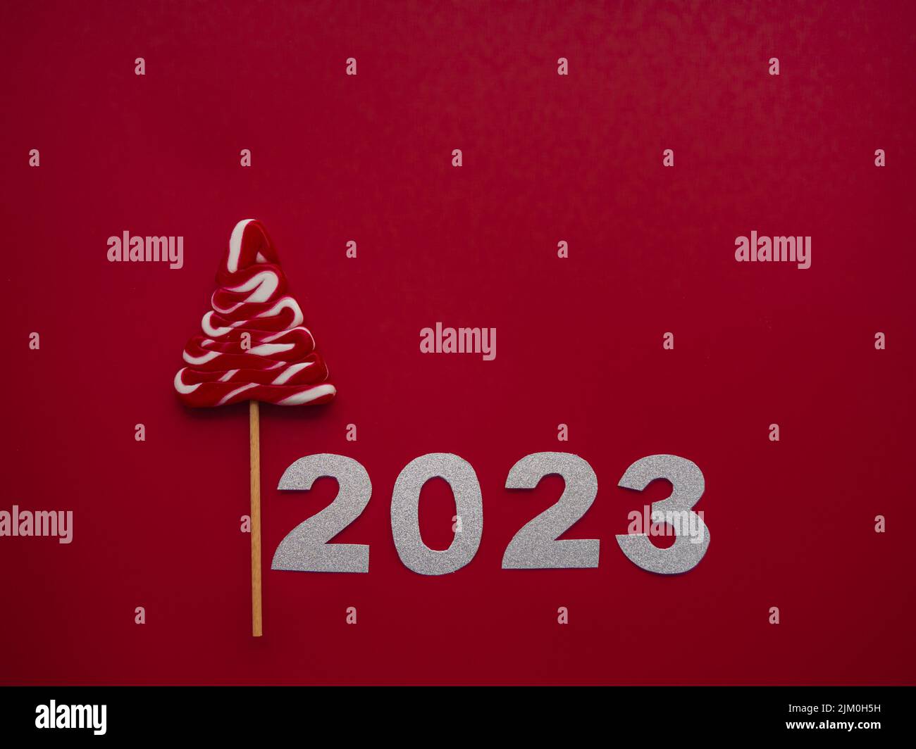 2023 et bonbon rouge blanc sous forme d'arbre de Noël sur fond rouge Banque D'Images
