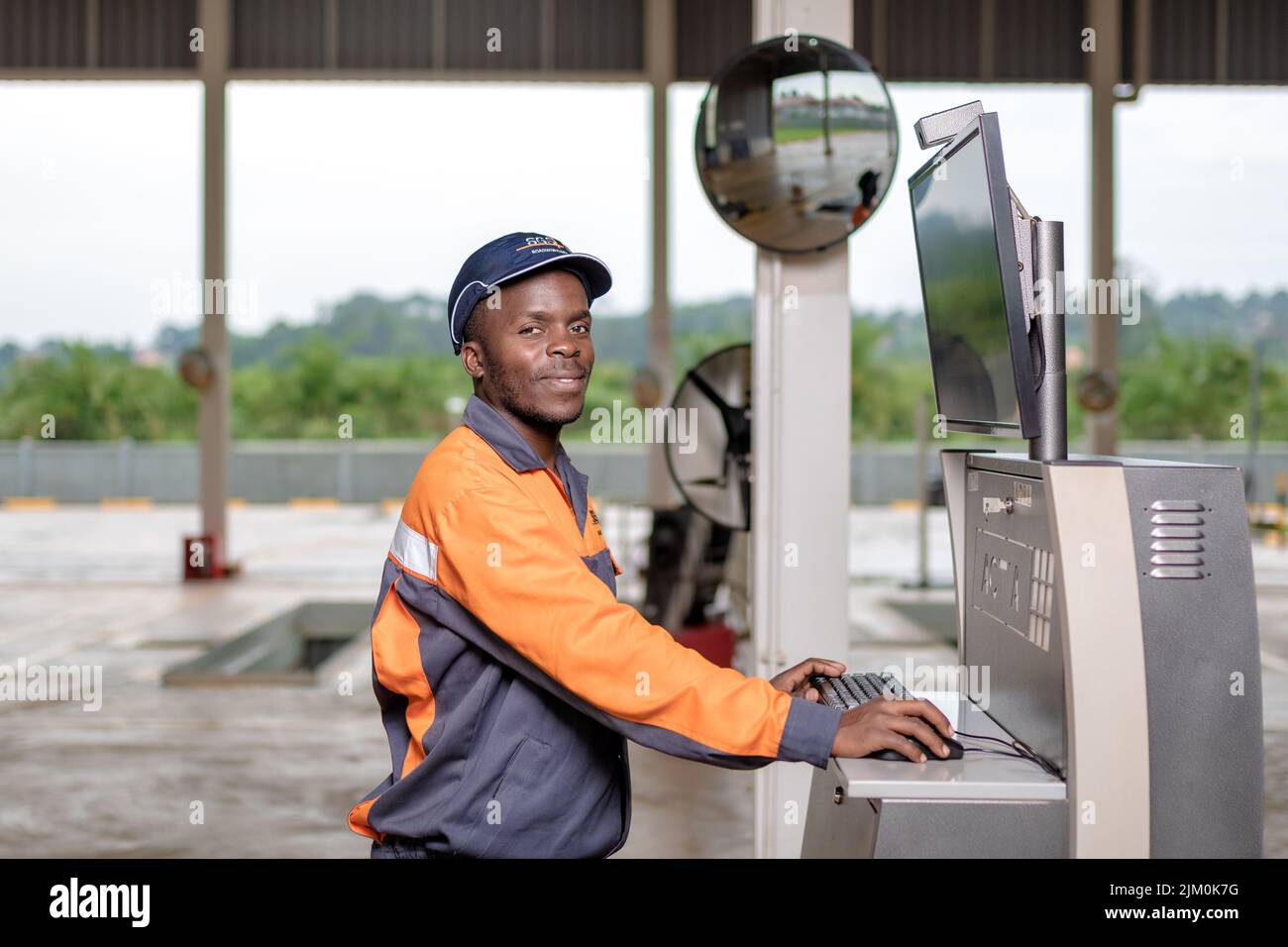 A Black male engineer operating a machine while wearing a gray and orange uniform Banque D'Images