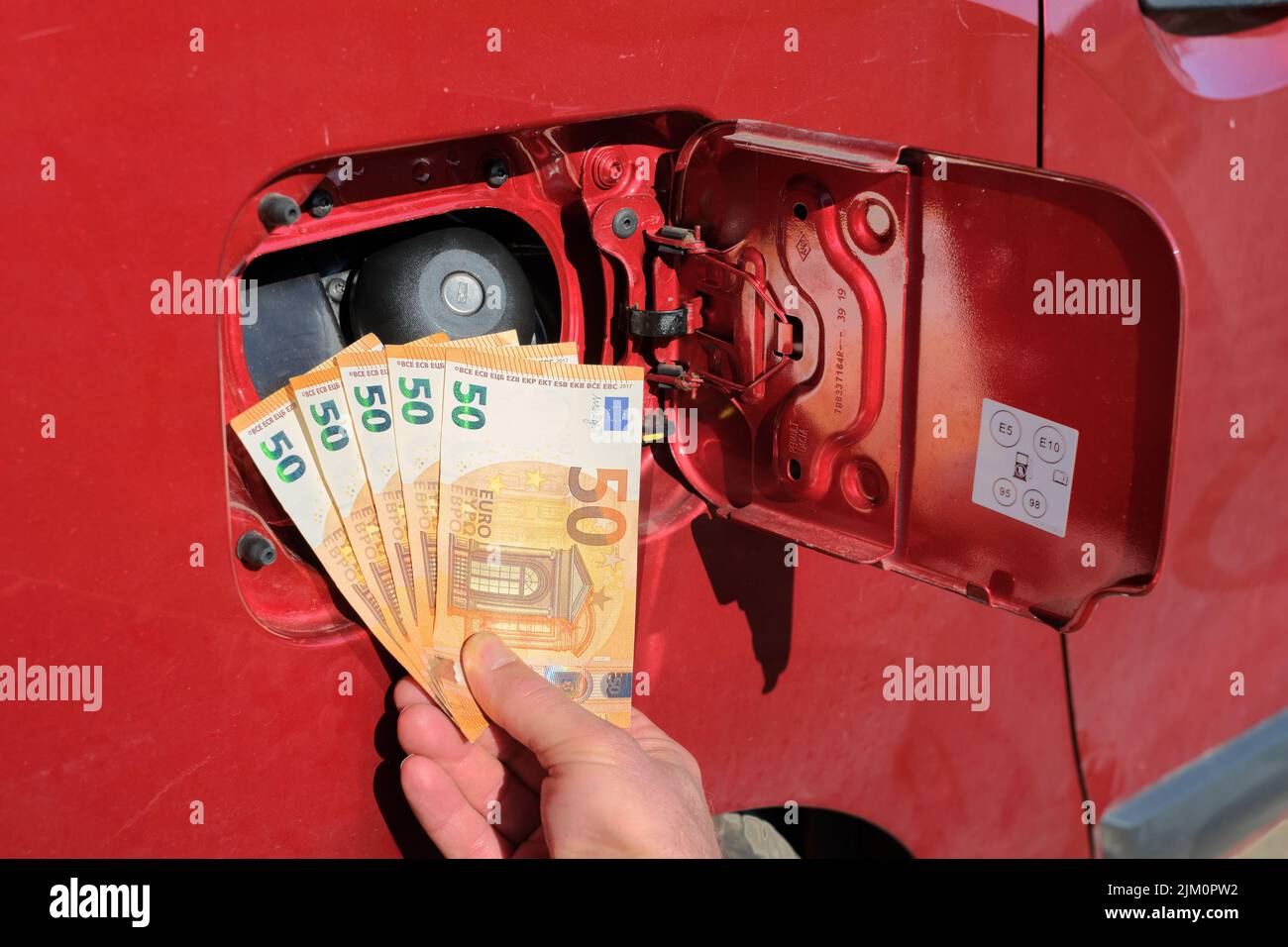 Une main tenant un paquet de cinquante billets d'euros en police d'un réservoir de carburant. Banque D'Images