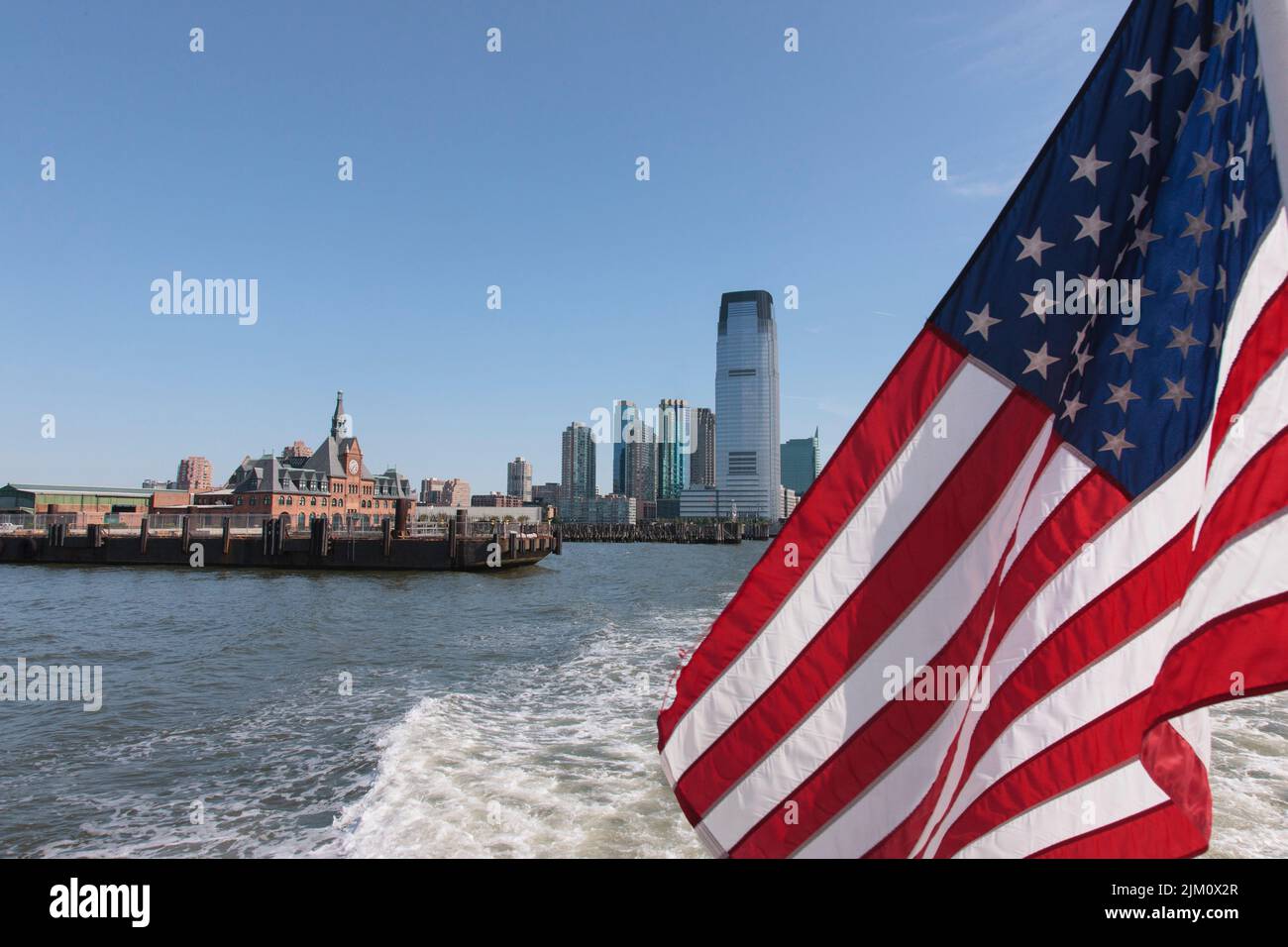 Un gros plan d'un drapeau américain agité contre une ville au bord de la mer Banque D'Images