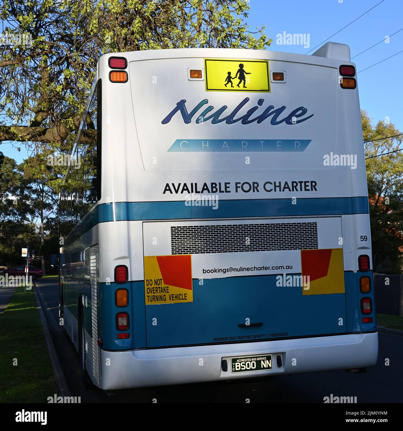 Arrière d'un bus charters Nuline, ou autocar, principalement blanc et bleu, dans une petite rue verdoyante de la banlieue de Melbourne Banque D'Images