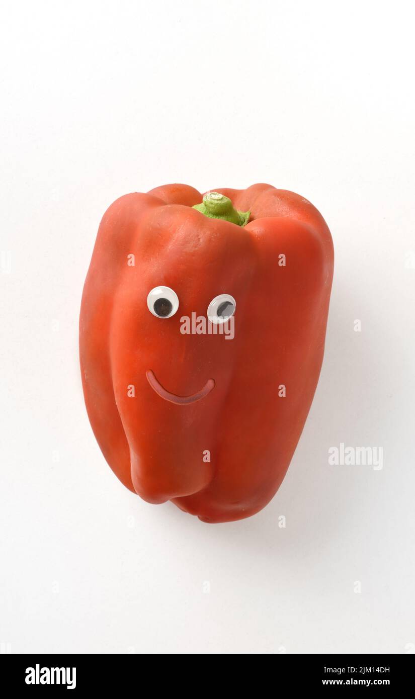 Poivre rouge frais avec visage sur fond blanc isolé. Fruits et légumes enfant concept de saine alimentation Banque D'Images