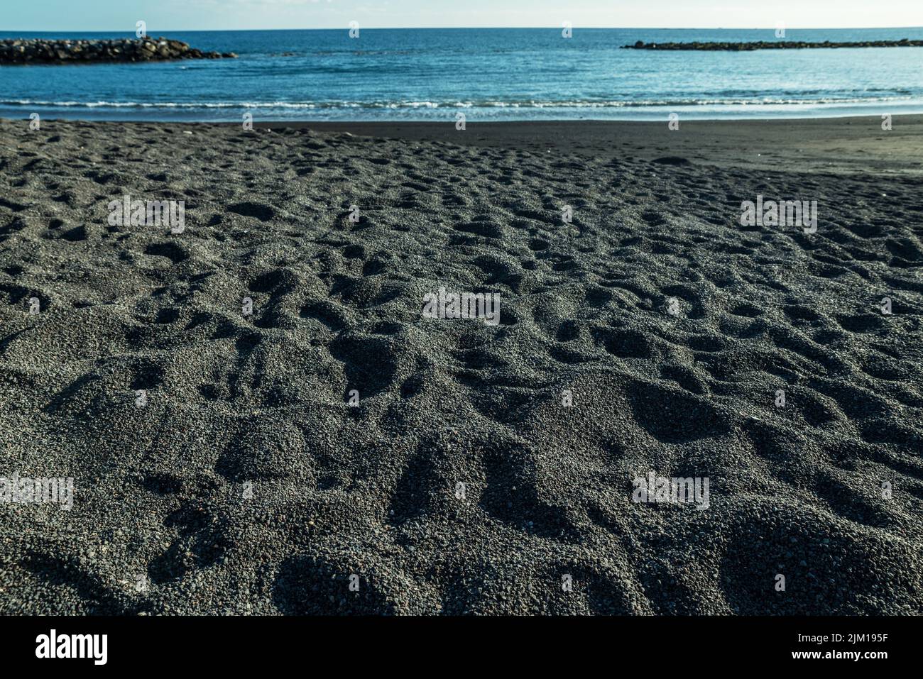 Mousse d'océan couvrant la magnifique plage de sable noir de l'île de Ténérife. Banque D'Images